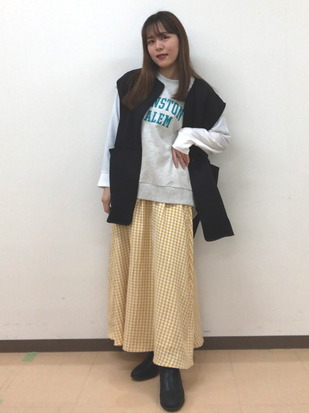 イエロー系のスカート、グレー系のベスト、ホワイト系のシャツ/ブラウスを着用したレディースの冬コーディネートの1枚目の写真