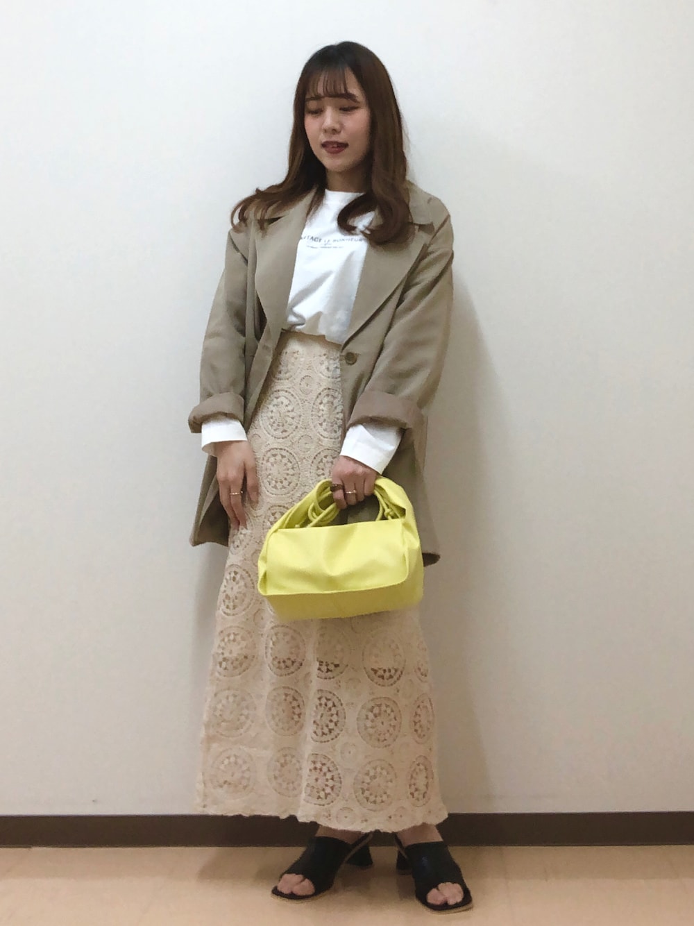 ベージュ系のテーラードジャケット、ベージュ系のスカート、グリーン系のショルダーバッグを着用したレディースの春コーディネートの1枚目の写真