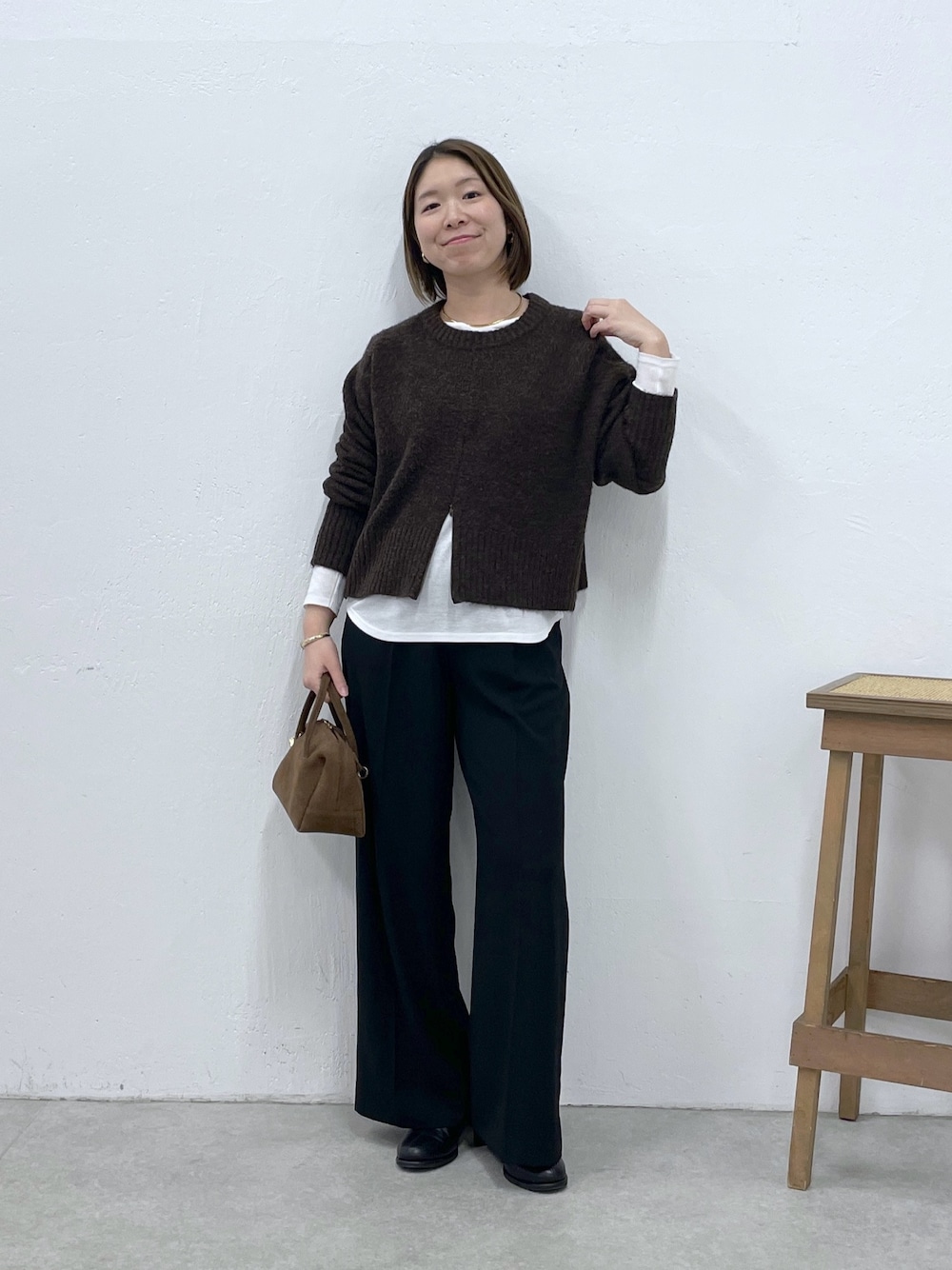 ホワイト系のTシャツ/カットソー、ブラウン系のニット/セーター、ブラック系のスラックスを着用したレディースの冬コーディネートの1枚目の写真