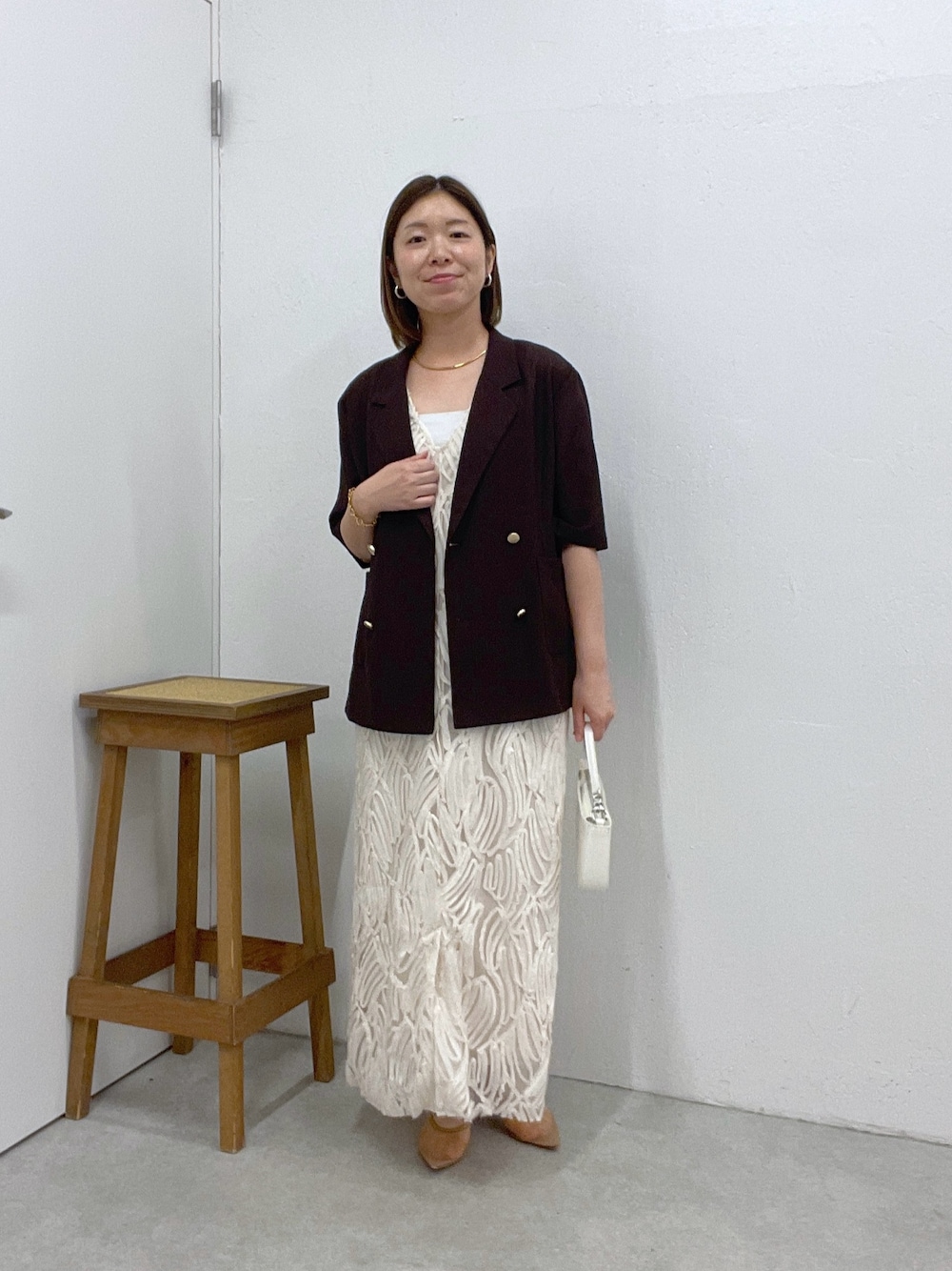 ホワイト系のワンピース、ブラウン系のテーラードジャケット、ホワイト系のショルダーバッグを着用したレディースの夏コーディネートの1枚目の写真