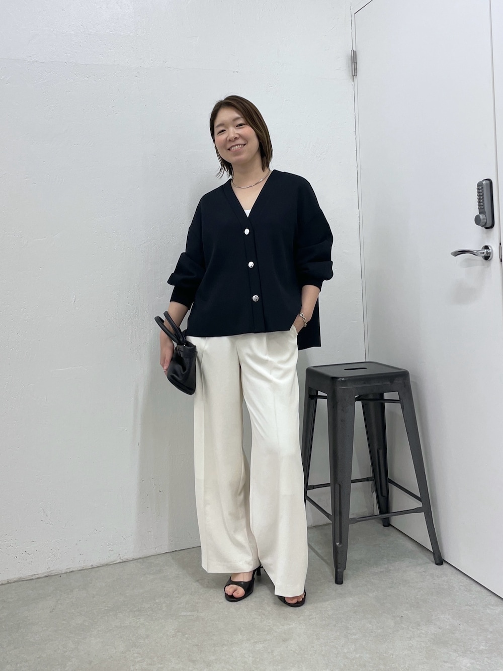 ブルー系のカーディガン/ボレロ、ホワイト系のスラックス、ブラック系のトートバッグを着用したレディースの春コーディネートの1枚目の写真