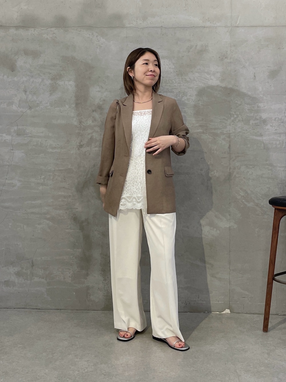 ベージュ系のテーラードジャケット、ホワイト系のキャミソール、ホワイト系のスラックスを着用したレディースの春コーディネートの1枚目の写真