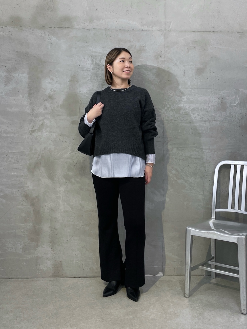 グレー系のニット/セーター、ホワイト系のTシャツ/カットソー、ブラック系のスラックスを着用したレディースの秋コーディネートの1枚目の写真