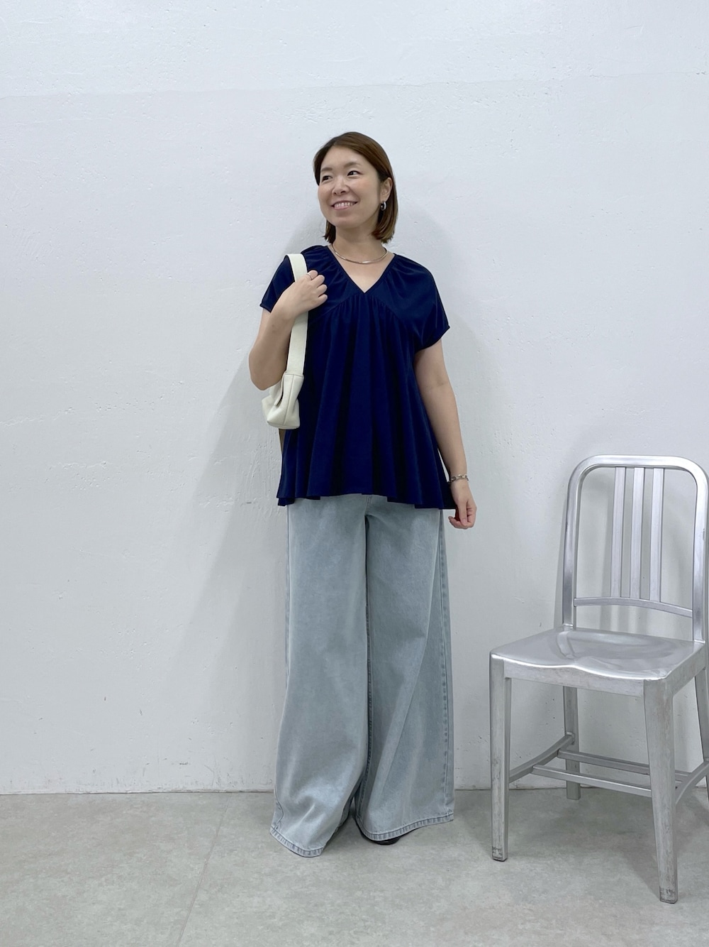 ブルー系のTシャツ/カットソー、ブルー系のデニムパンツ、ホワイト系のショルダーバッグを着用したレディースの夏コーディネートの1枚目の写真