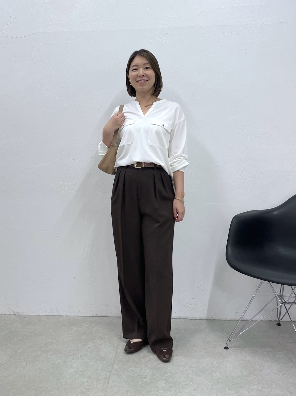 ホワイト系のTシャツ/カットソー、ブラウン系のスラックス、ベージュ系のショルダーバッグを着用したレディースの夏コーディネートの1枚目の写真