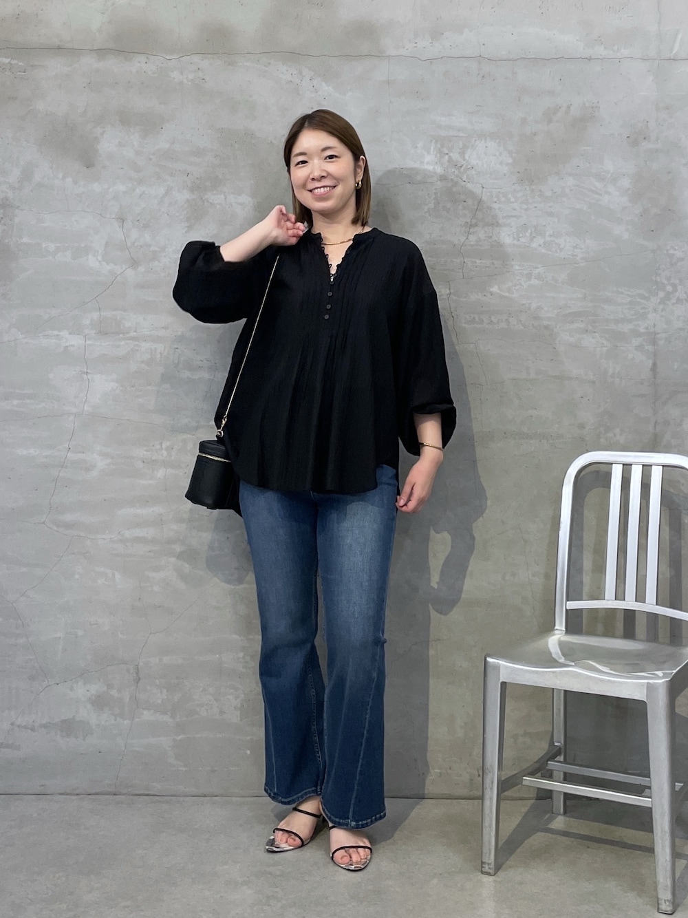 ブルー系のデニムパンツ、ブラック系のシャツ/ブラウス、ブラック系のショルダーバッグを着用したレディースの夏コーディネートの1枚目の写真