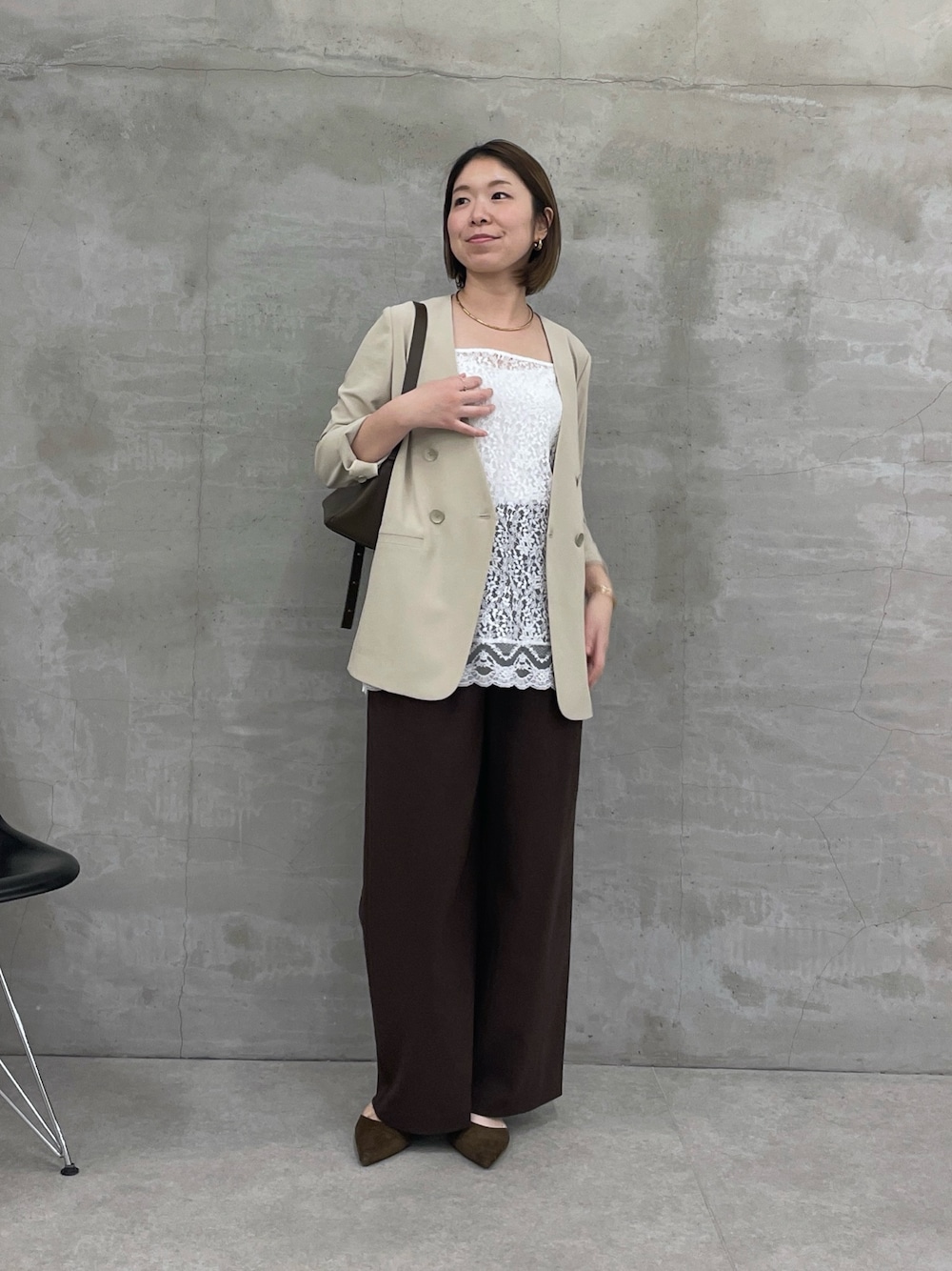 ベージュ系のノーカラージャケット、ホワイト系のキャミソール、ブラウン系のスラックスを着用したレディースの冬コーディネートの1枚目の写真