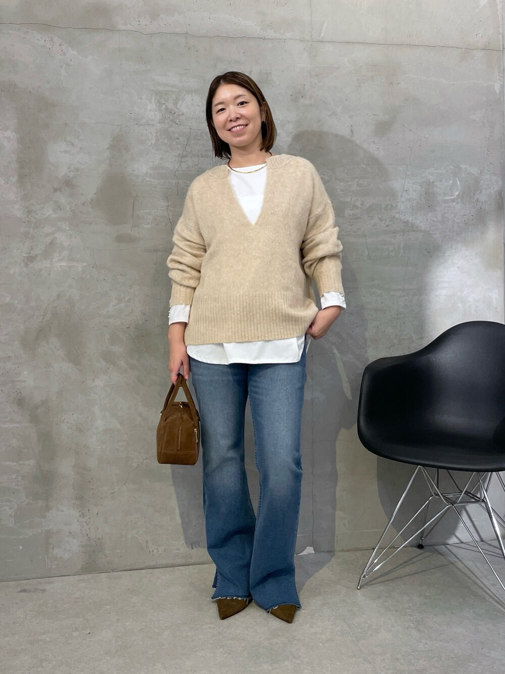 ベージュ系のニット/セーター、ブルー系のデニムパンツ、ブラウン系のバッグを着用したレディースの秋コーディネートの1枚目の写真