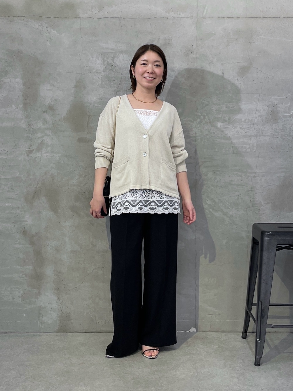 ベージュ系のカーディガン/ボレロ、ホワイト系のキャミソール、ブラック系のスラックスを着用したレディースの春コーディネートの1枚目の写真