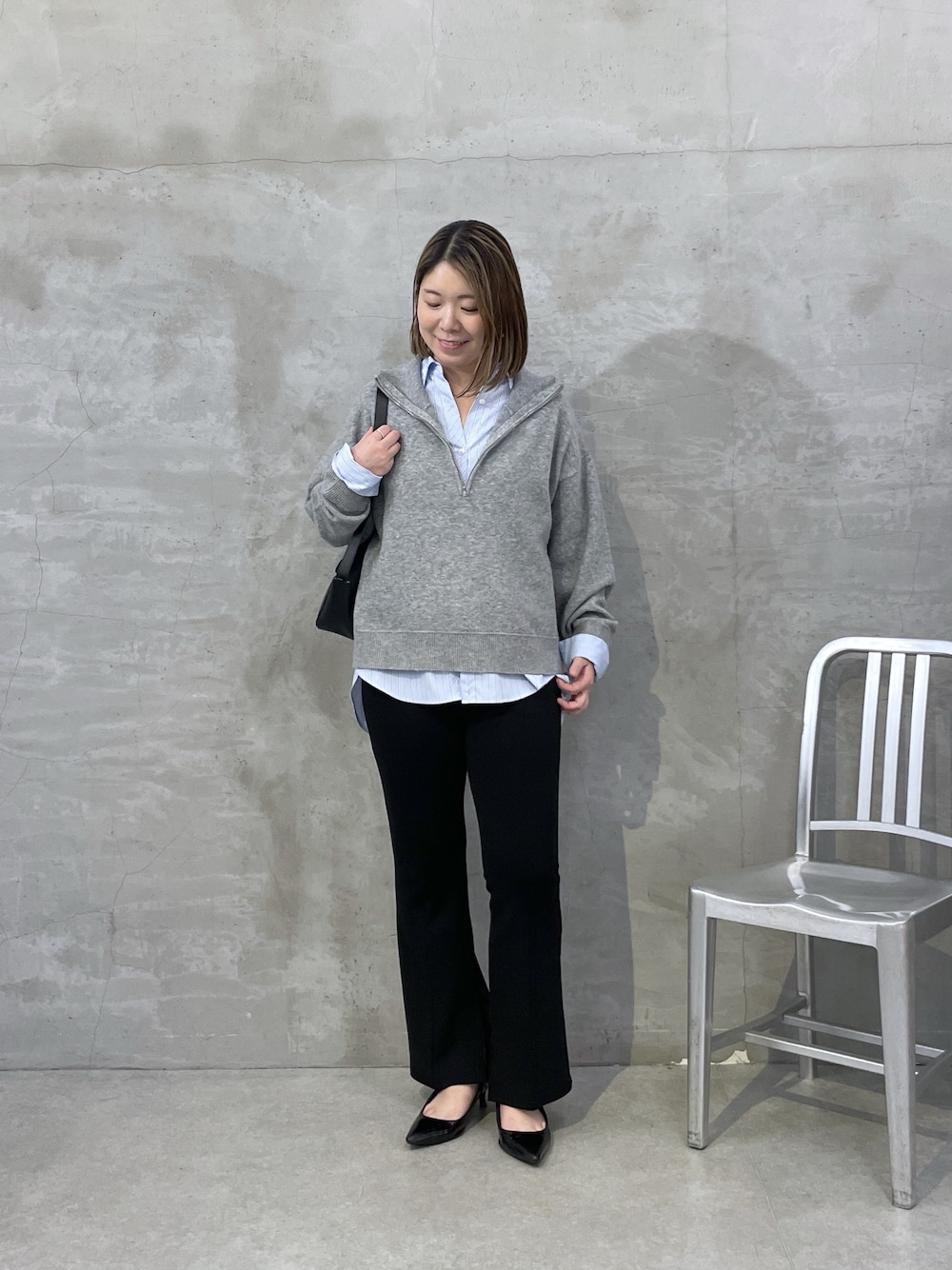 グレー系のニット/セーター、ブルー系のシャツ/ブラウス、ブラック系のスラックスを着用したレディースの秋コーディネートの1枚目の写真