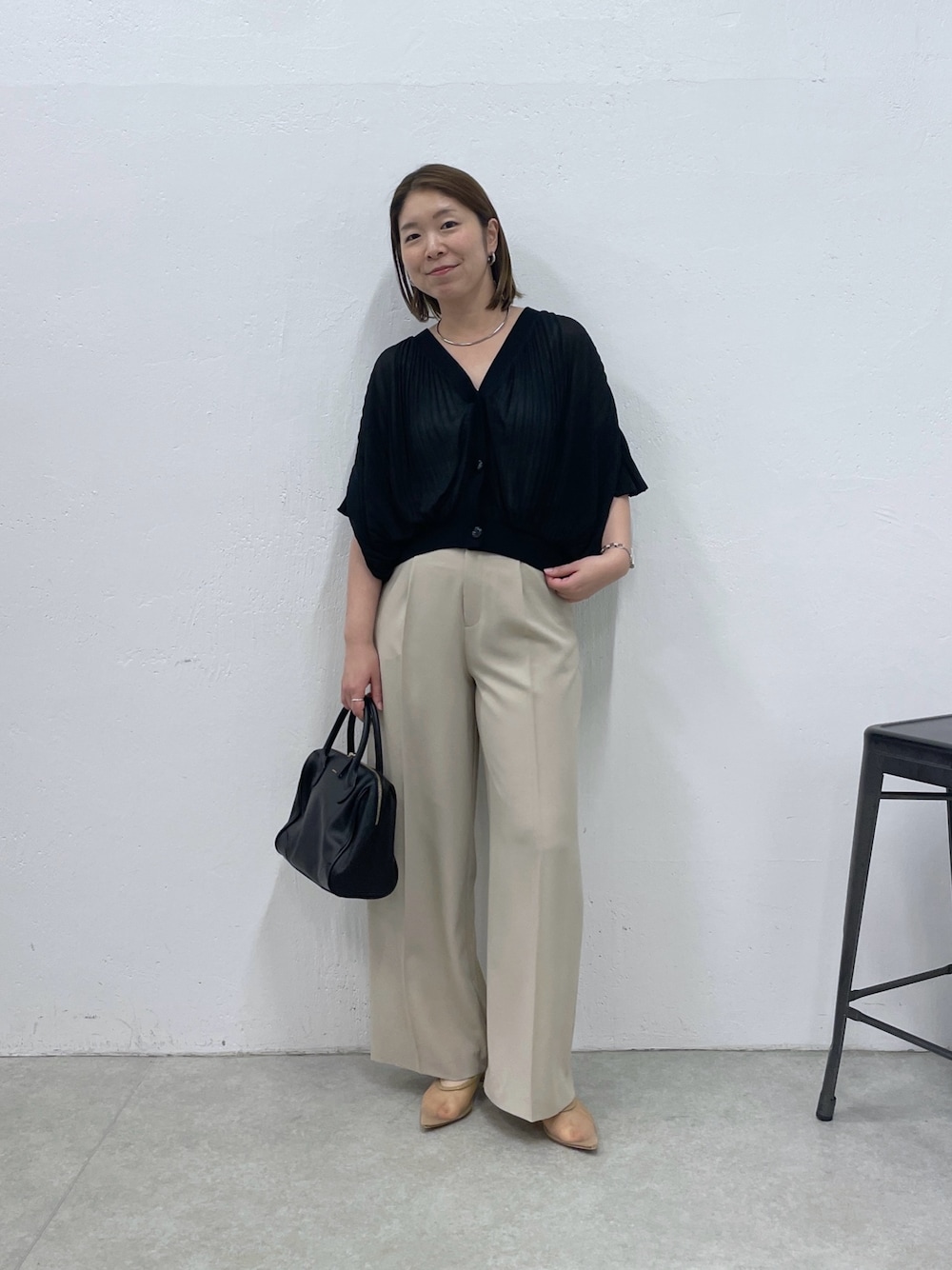 ブラック系のTシャツ/カットソー、ベージュ系のスラックス、ブラック系のボストンバッグを着用したレディースの夏コーディネートの1枚目の写真