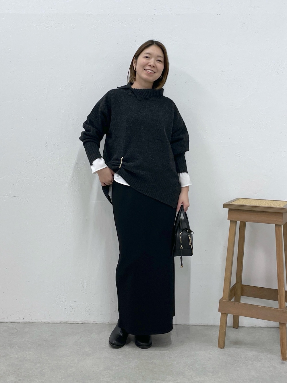 グレー系のニット/セーター、ホワイト系のシャツ/ブラウス、ブラック系のスカートを着用したレディースの冬コーディネートの1枚目の写真