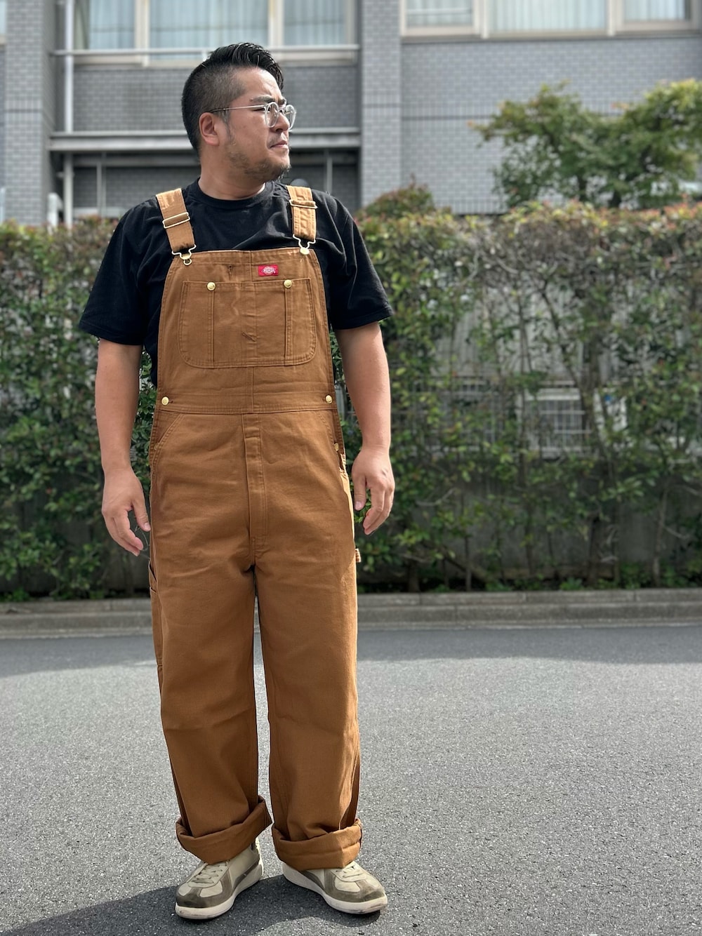 ブラック系のTシャツ/カットソー、ホワイト系のスニーカー、ブラウン系のサロペット/オーバーオールを着用したメンズの秋コーディネートの1枚目の写真