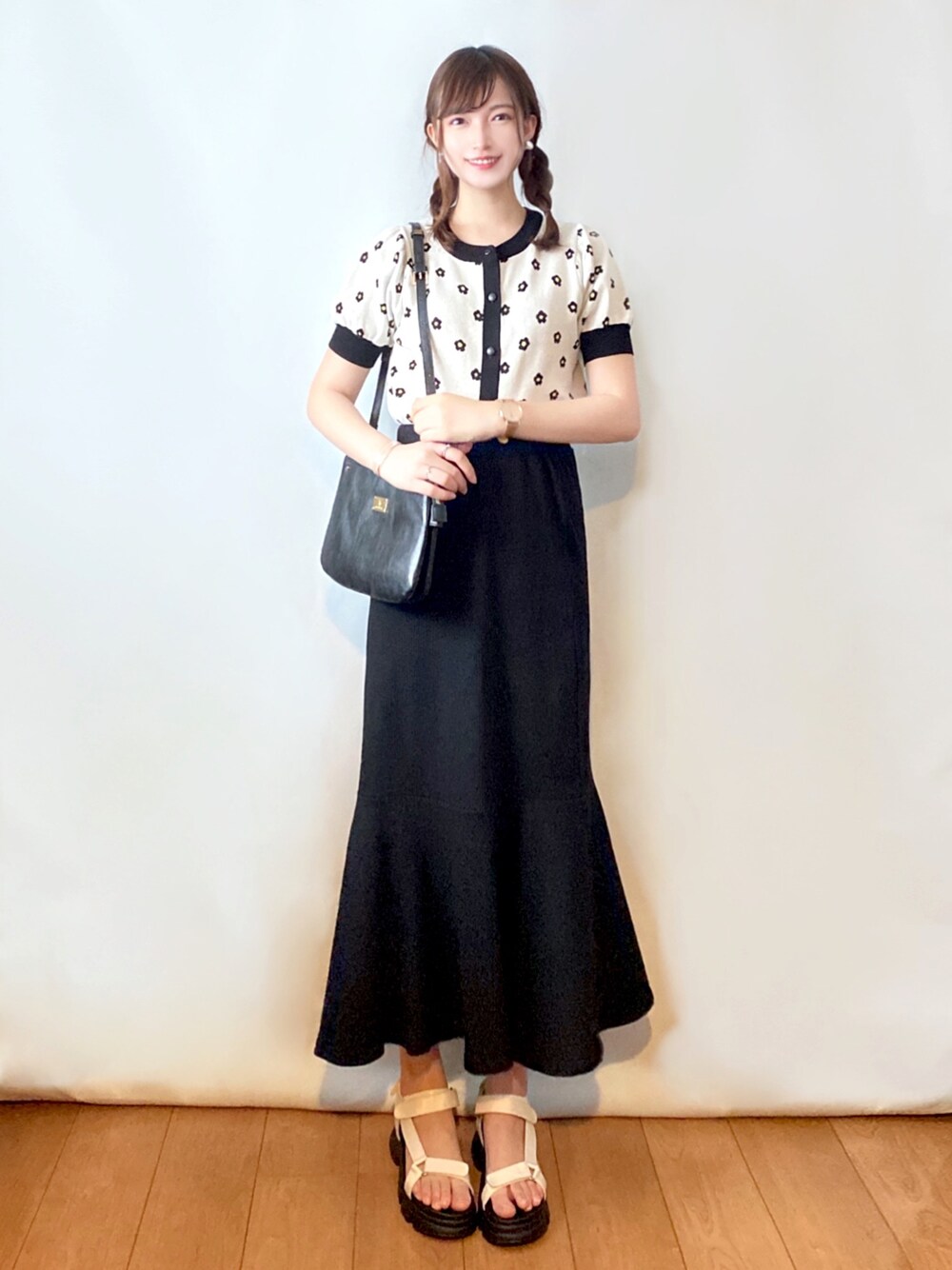 ホワイト系のカーディガン/ボレロ、ブラック系のスカート、ブラック系のショルダーバッグを着用したレディースの夏コーディネートの1枚目の写真