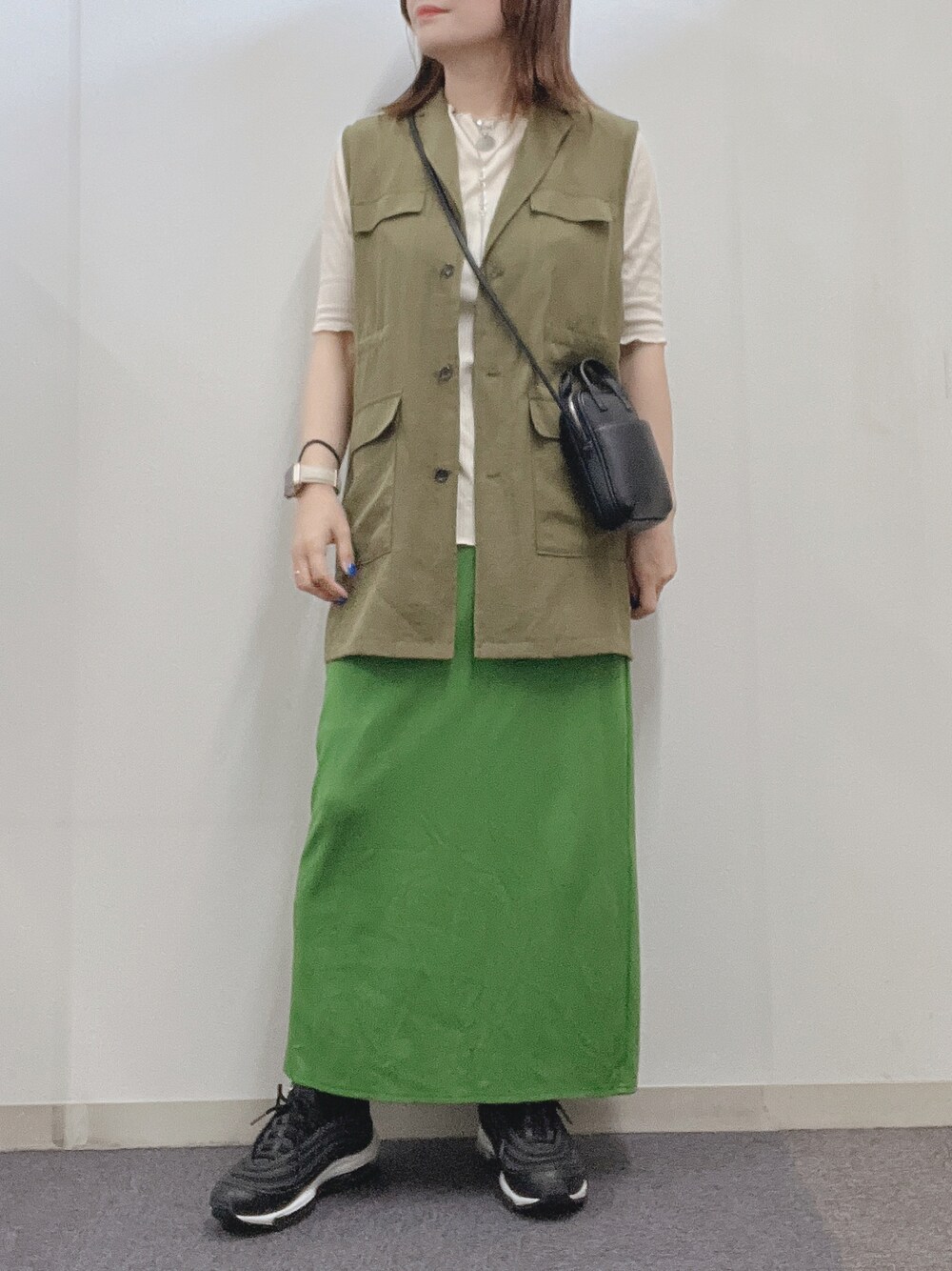 グリーン系のベスト、グリーン系のスカート、ホワイト系のTシャツ/カットソーを着用したレディースの春コーディネートの1枚目の写真