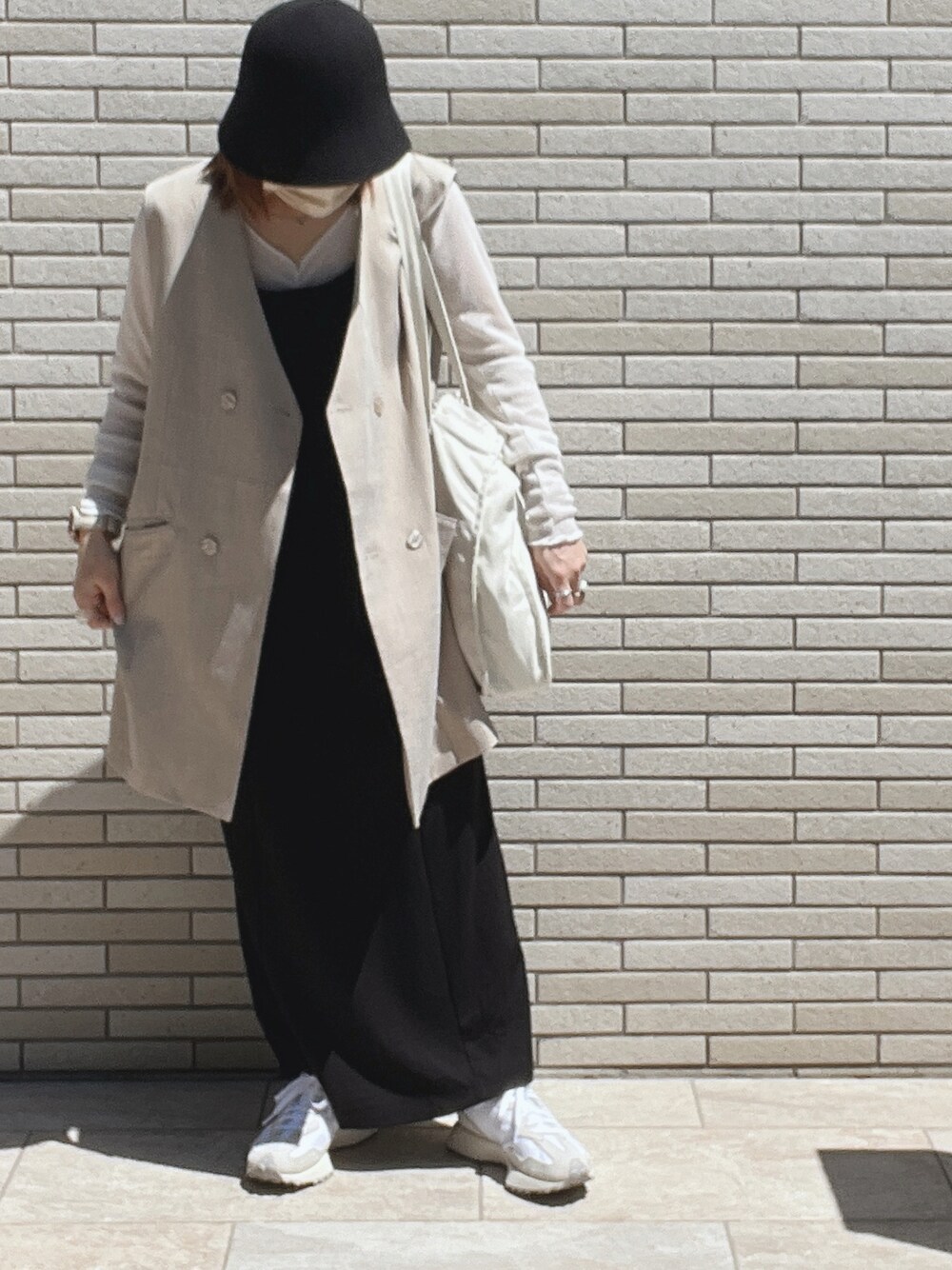 グレー系のベスト、ブラック系のワンピース、ホワイト系のTシャツ/カットソーを着用したレディースの春コーディネートの1枚目の写真