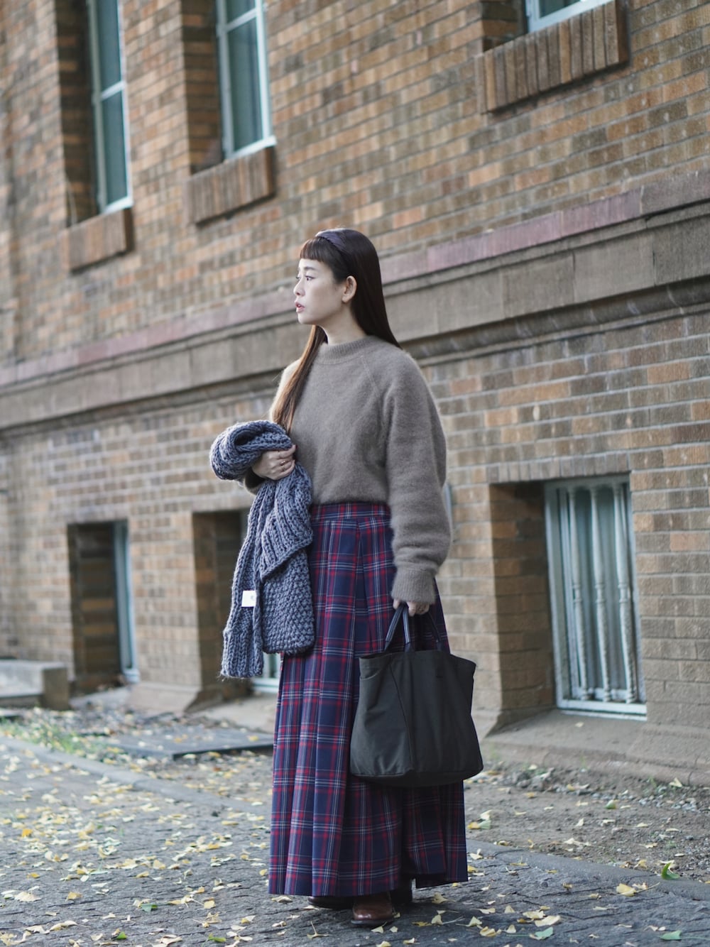 ブラウン系のニット/セーター、グリーン系のトートバッグ、ブラウン系のドレスシューズを着用したレディースの秋コーディネートの1枚目の写真