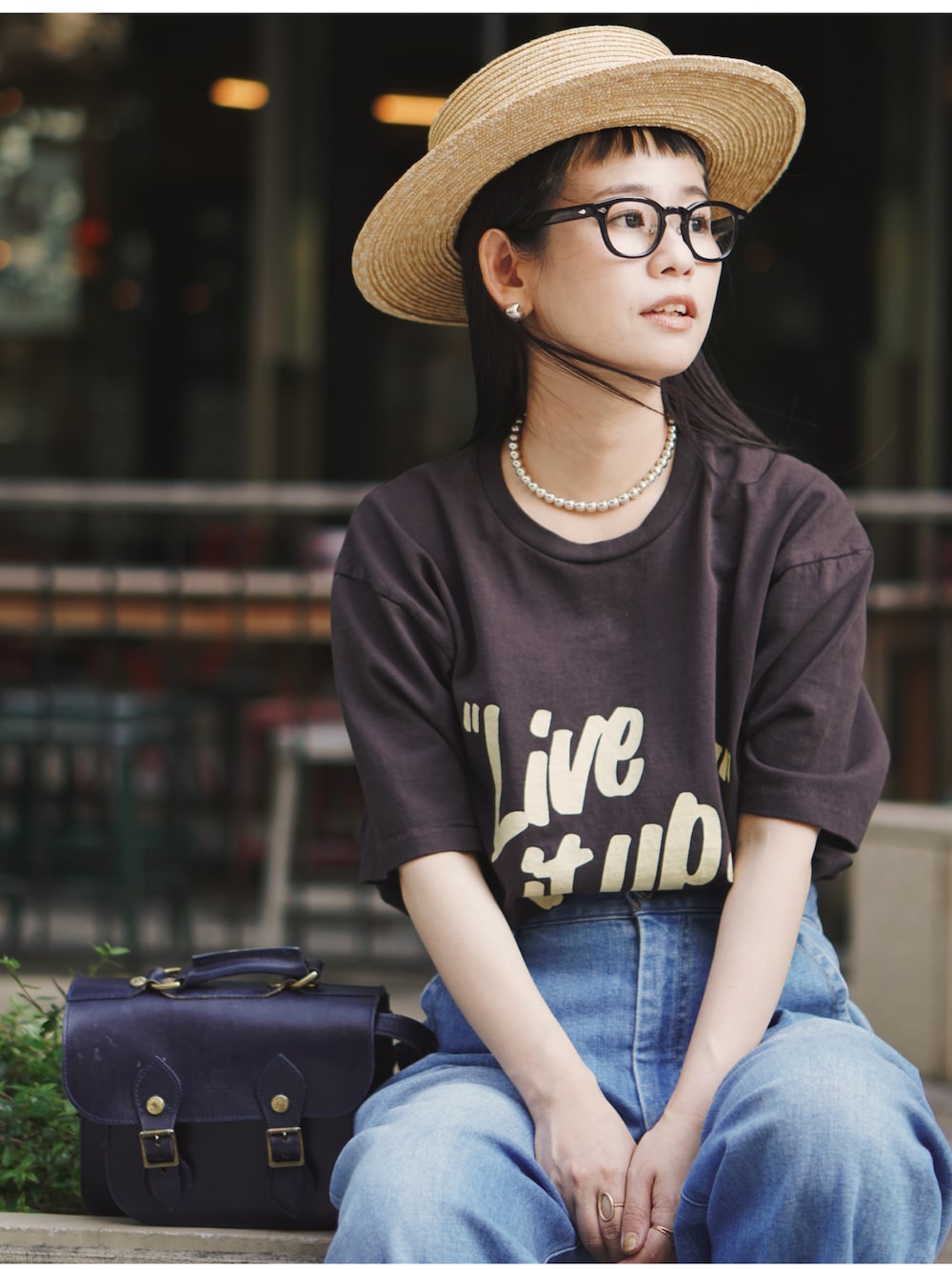 ブルー系のデニムパンツ、ブラック系のショルダーバッグ、ブラウン系のTシャツ/カットソーを着用したレディースの夏コーディネートの1枚目の写真
