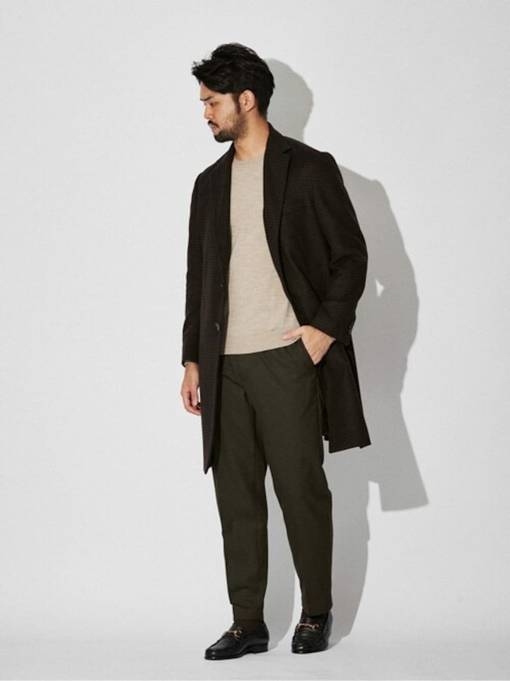 ブラウン系のチェスターコート、ベージュ系のニット/セーター、グリーン系のスラックスを着用したメンズの秋コーディネートの1枚目の写真