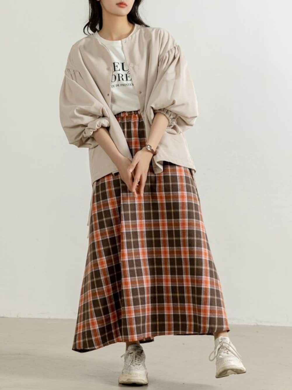 オレンジ系のスカート、ホワイト系のブルゾンを着用したレディースの秋コーディネートの1枚目の写真