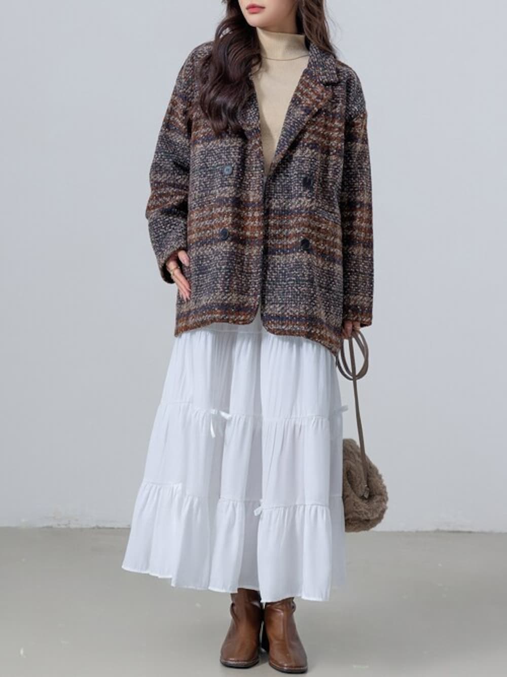 ホワイト系のスカート、ホワイト系のニット/セーター、ブラウン系のピーコートを着用したレディースの冬コーディネートの1枚目の写真