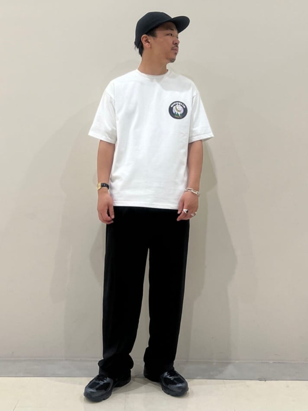 ブラック系のスラックス、ホワイト系のTシャツ/カットソー、ブラック系のスニーカーを着用したメンズの春コーディネートの1枚目の写真
