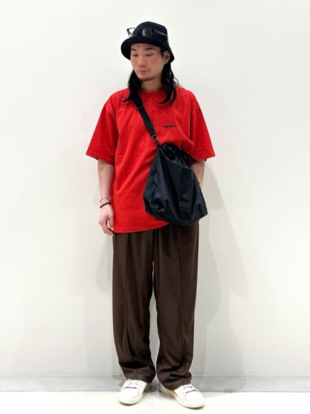 ホワイト系のスニーカー、レッド系のTシャツ/カットソー、ブラウン系のスラックスを着用したメンズの春コーディネートの1枚目の写真