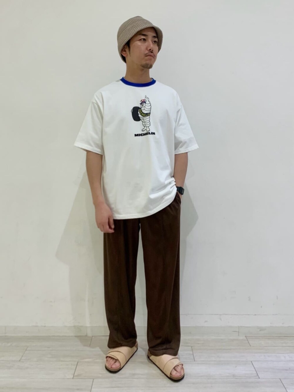 ブラウン系のスラックス、ベージュ系のサンダル、ホワイト系のTシャツ/カットソーを着用したメンズの春コーディネートの1枚目の写真
