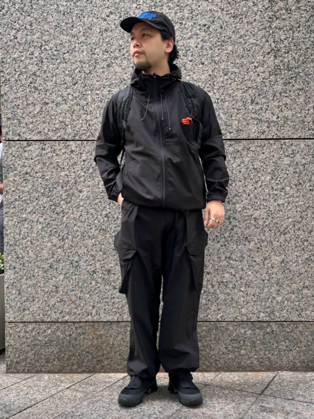 ブラック系のカーゴパンツ、ブラック系のマウンテンパーカー、ブラック系のスニーカーを着用したメンズの秋コーディネートの1枚目の写真