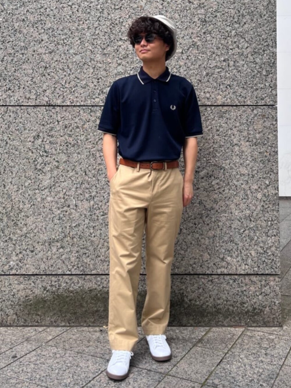 ホワイト系のスニーカー、ベージュ系のチノパンツ、ブルー系のポロシャツを着用したメンズの夏コーディネートの1枚目の写真