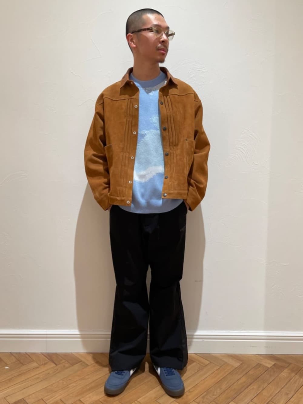 ブラウン系のブルゾン、ブルー系のニット/セーター、ブラック系のカーゴパンツを着用したメンズの冬コーディネートの1枚目の写真