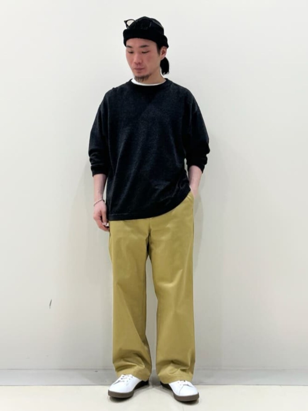 ブラック系のニット/セーター、ホワイト系のスニーカー、ベージュ系のスラックスを着用したメンズの春コーディネートの1枚目の写真