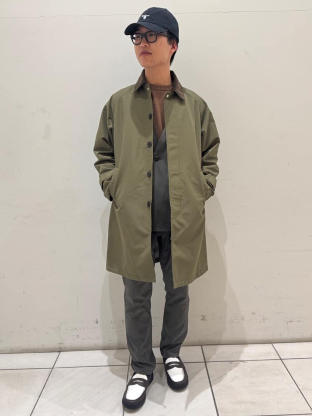 グリーン系のステンカラーコート、グレー系のスラックスを着用したメンズの春コーディネートの1枚目の写真