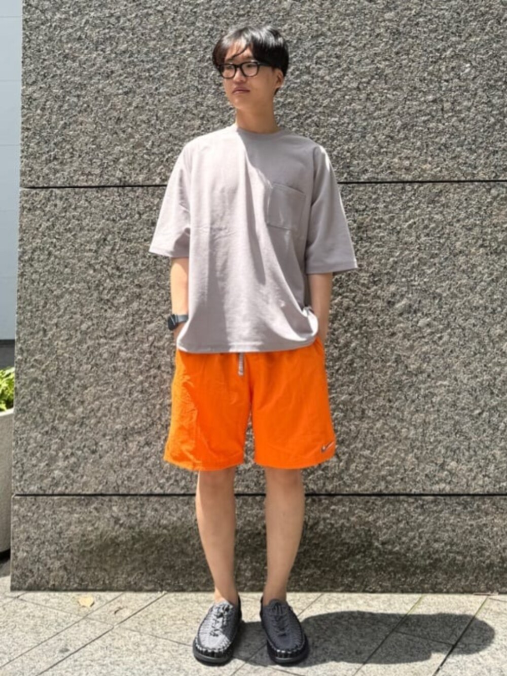 グレー系のTシャツ/カットソー、オレンジ系のカーゴパンツ、グレー系のサンダルを着用したメンズの夏コーディネートの1枚目の写真