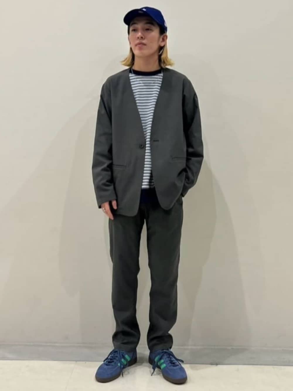 グレー系のスラックス、グレー系のノーカラージャケット、ブルー系のスニーカーを着用したメンズの春コーディネートの1枚目の写真