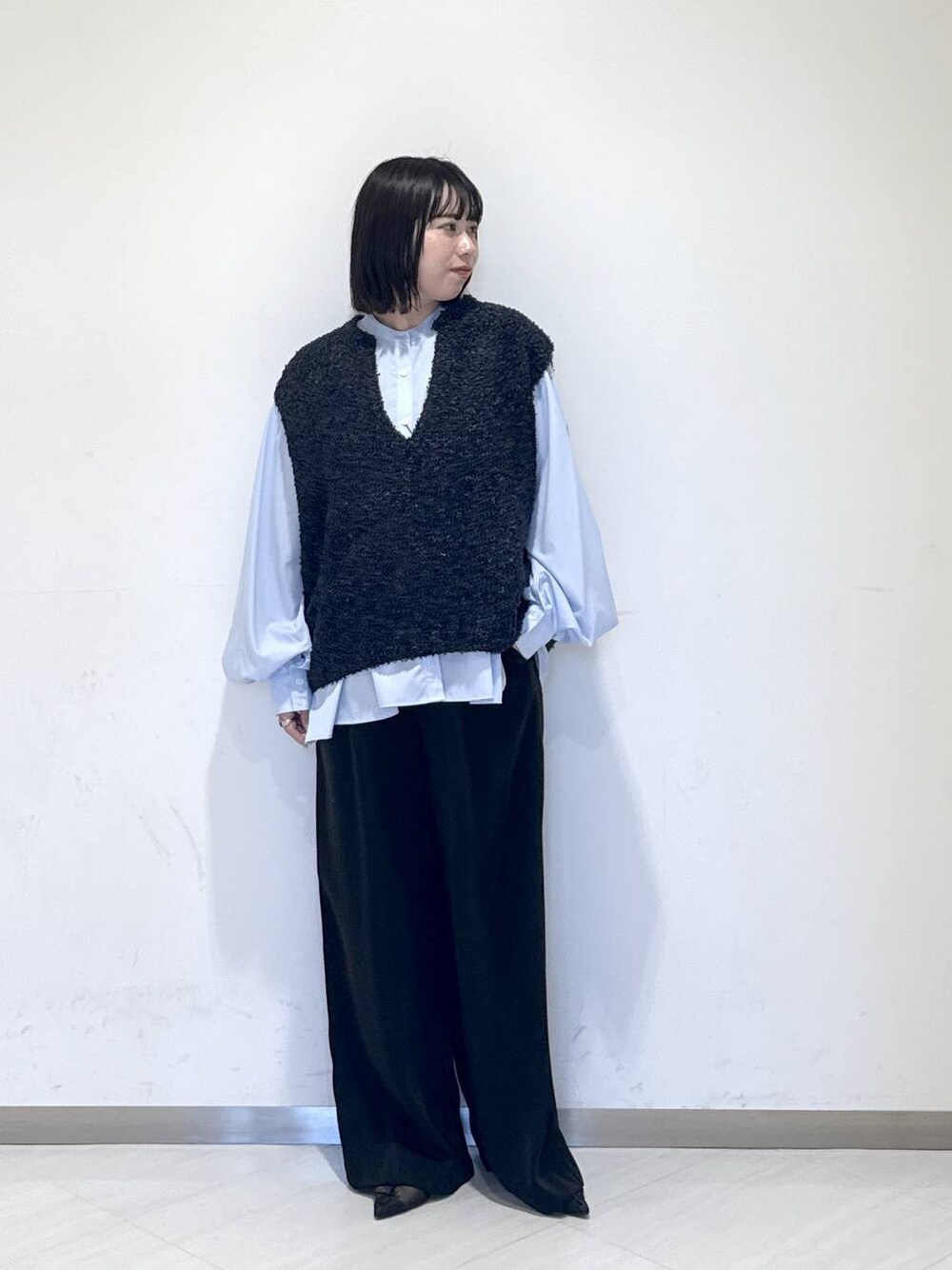 ブラック系のスラックス、ブルー系のTシャツ/カットソー、ブルー系のベストを着用したレディースの冬コーディネートの1枚目の写真