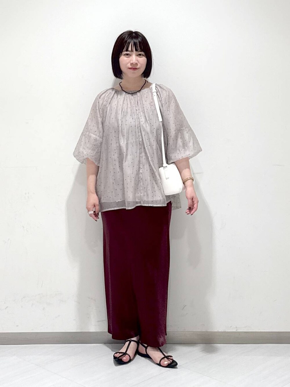 ブラック系のサンダル、ホワイト系のハンドバッグ、レッド系のスカートを着用したレディースの夏コーディネートの1枚目の写真