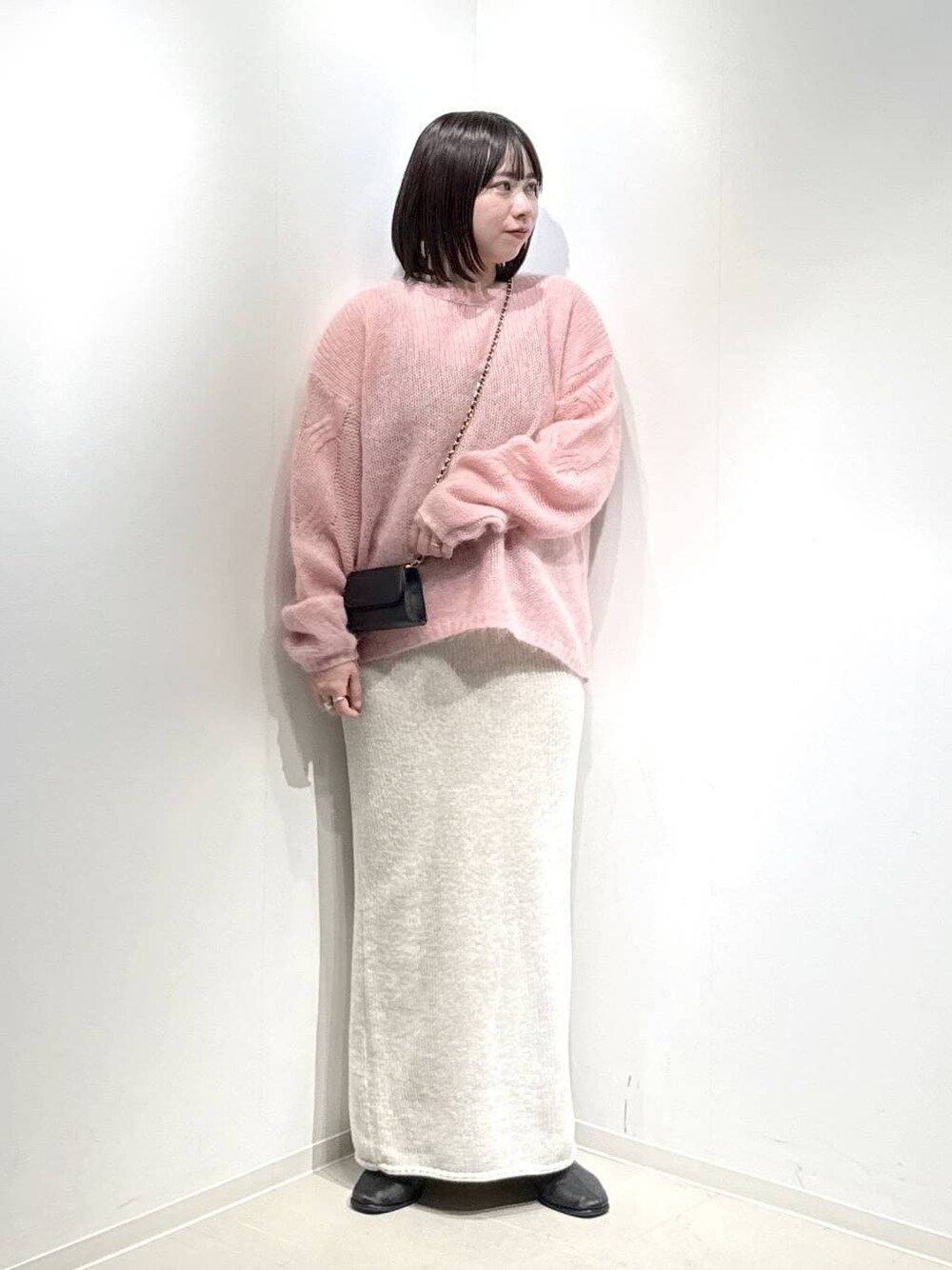 ベージュ系のセットアップ、ピンク系のニット/セーター、ブラック系のブーツを着用したレディースの冬コーディネートの1枚目の写真