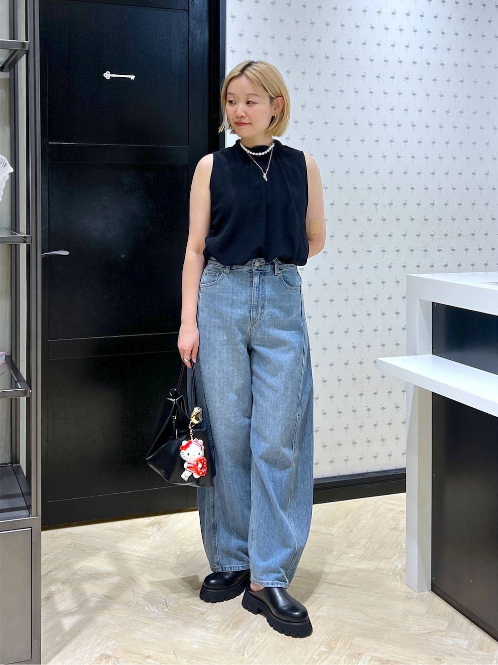 ブラック系のスリッポン、ブルー系のデニムパンツ、ブラック系のショルダーバッグを着用したレディースの夏コーディネートの1枚目の写真