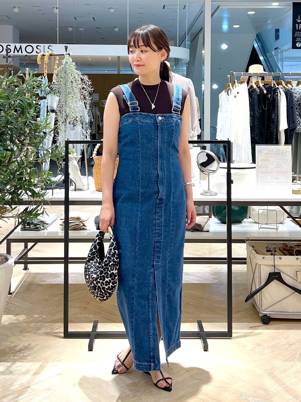 ブルー系のジャンパースカート、ブラック系のサンダル、ブラウン系のニット/セーターを着用したレディースの夏コーディネートの1枚目の写真