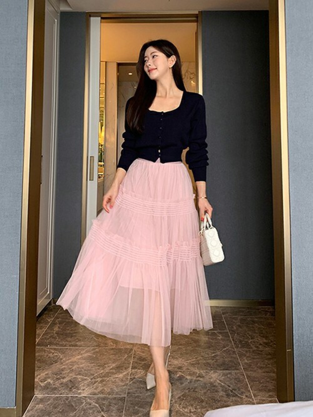 ピンク系のスカートを着用したレディースの春コーディネートの1枚目の写真