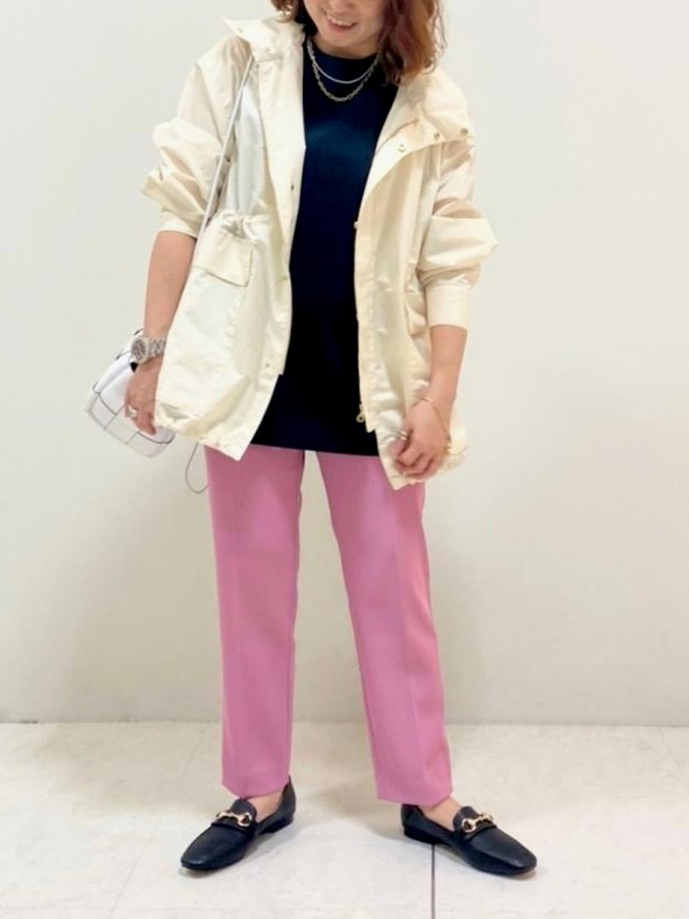 ホワイト系のマウンテンパーカー、ブラック系のシャツ/ブラウス、ホワイト系のハンドバッグを着用したレディースの春コーディネートの1枚目の写真