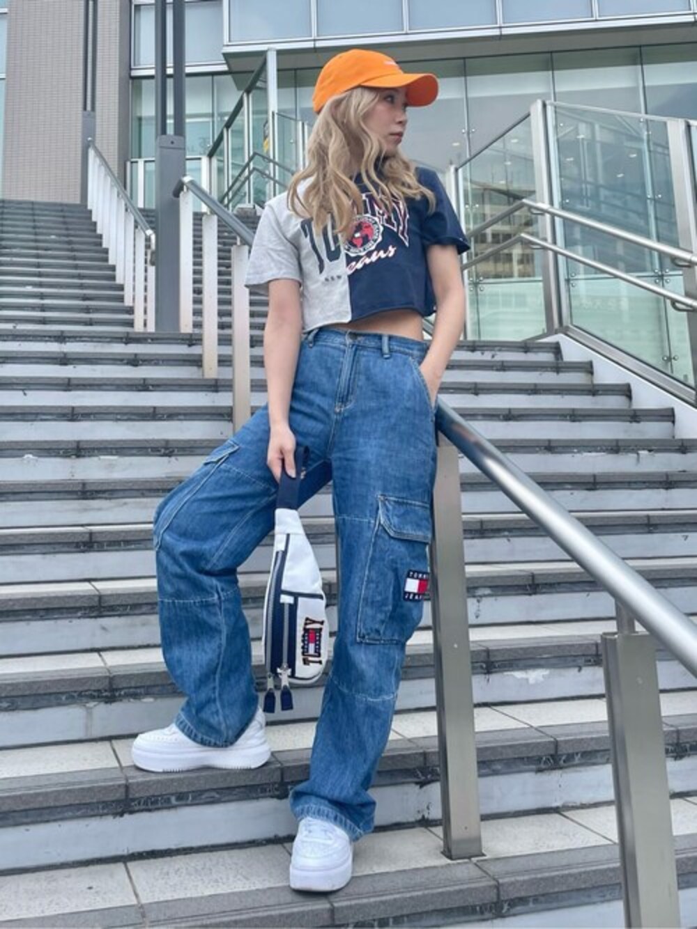 ブルー系のTシャツ/カットソー、ホワイト系のボディバッグ/ウエストポーチ、オレンジ系のキャップを着用したメンズの春コーディネートの1枚目の写真