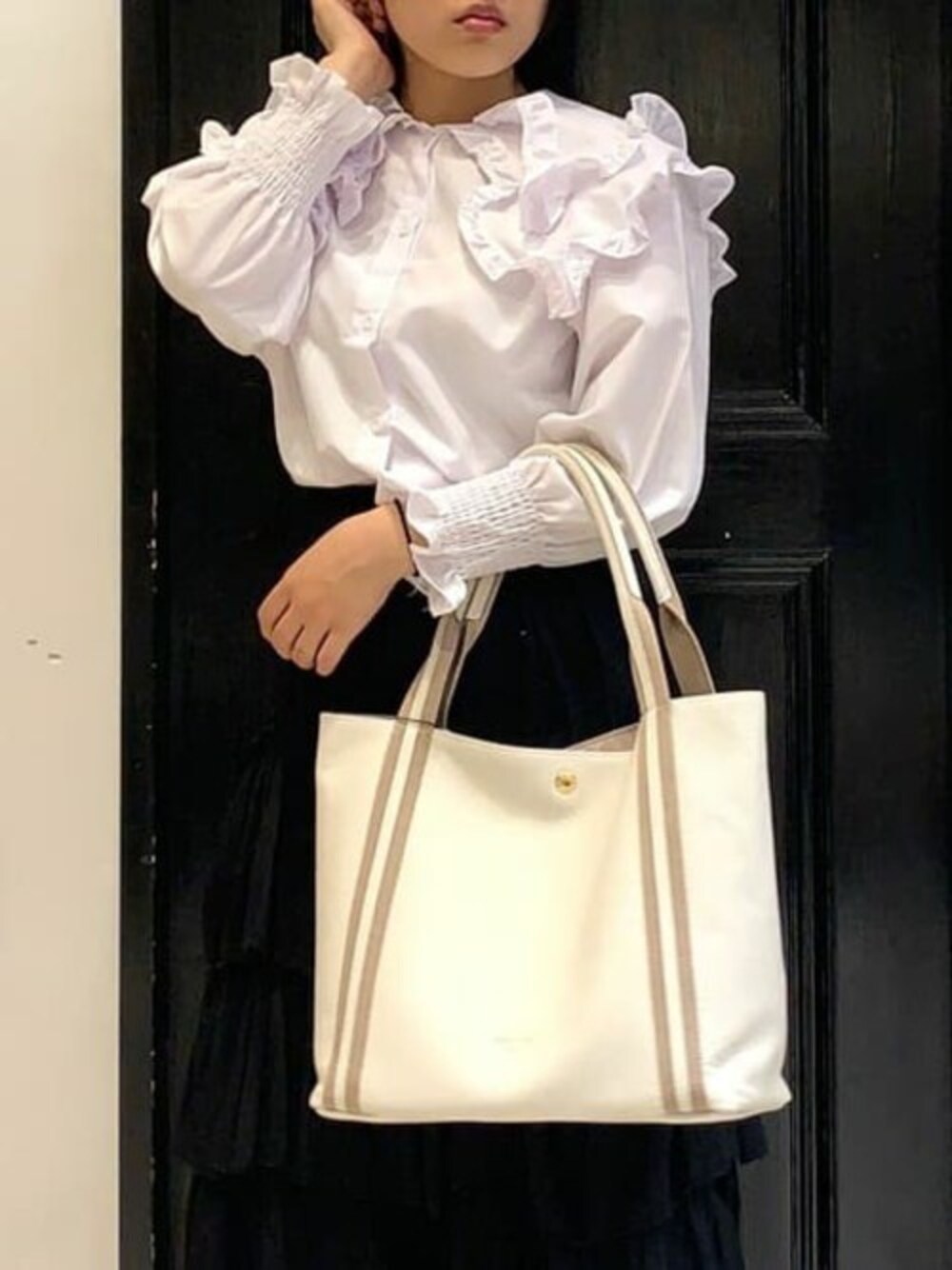 ホワイト系のトートバッグを着用したレディースの冬コーディネートの1枚目の写真