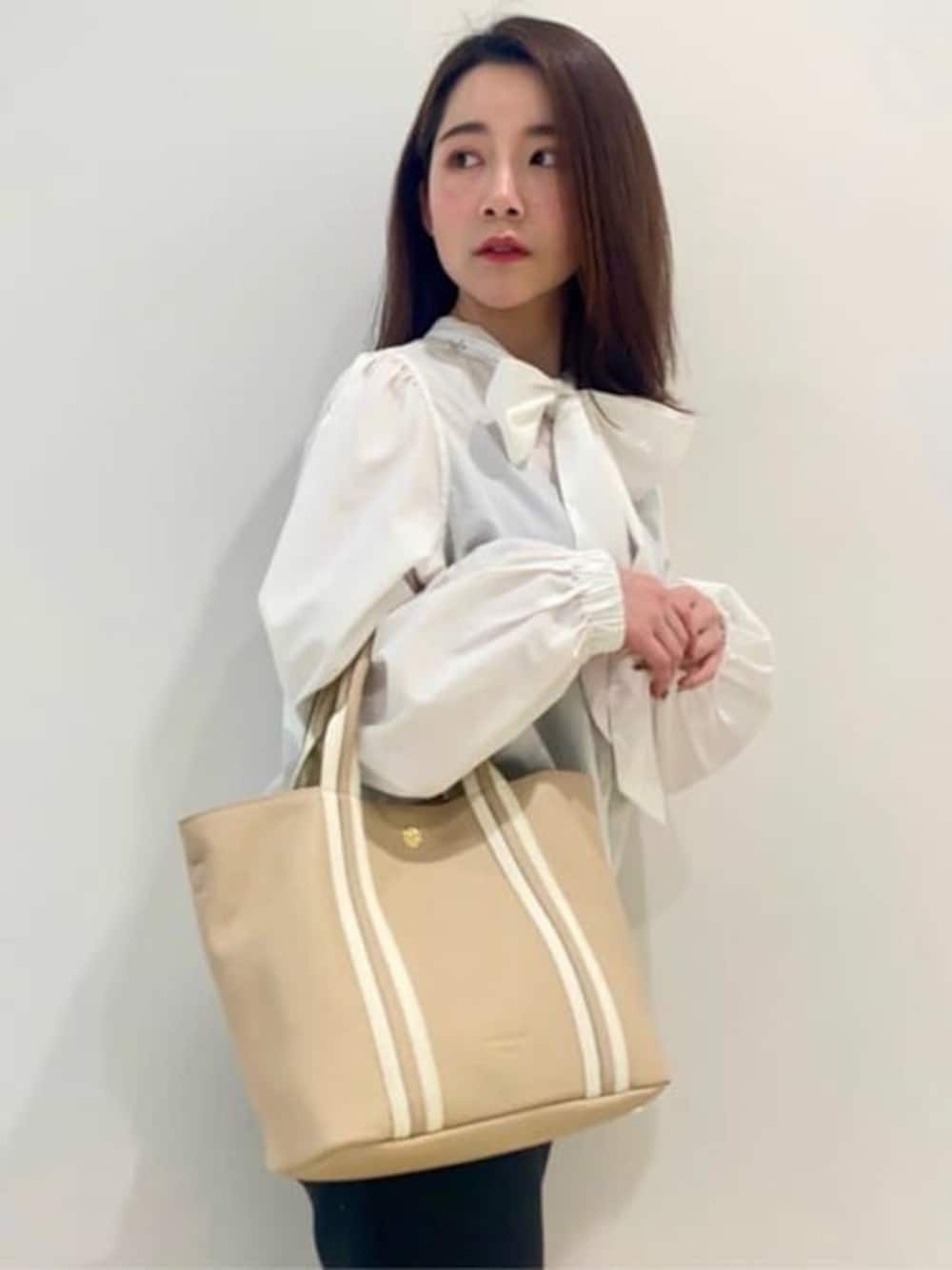 ベージュ系のトートバッグを着用したレディースの冬コーディネートの1枚目の写真