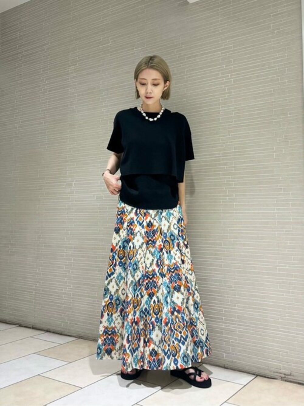 ブルー系のスカート、ブラック系のTシャツ/カットソー、ブラック系のサンダルを着用したレディースの夏コーディネートの1枚目の写真