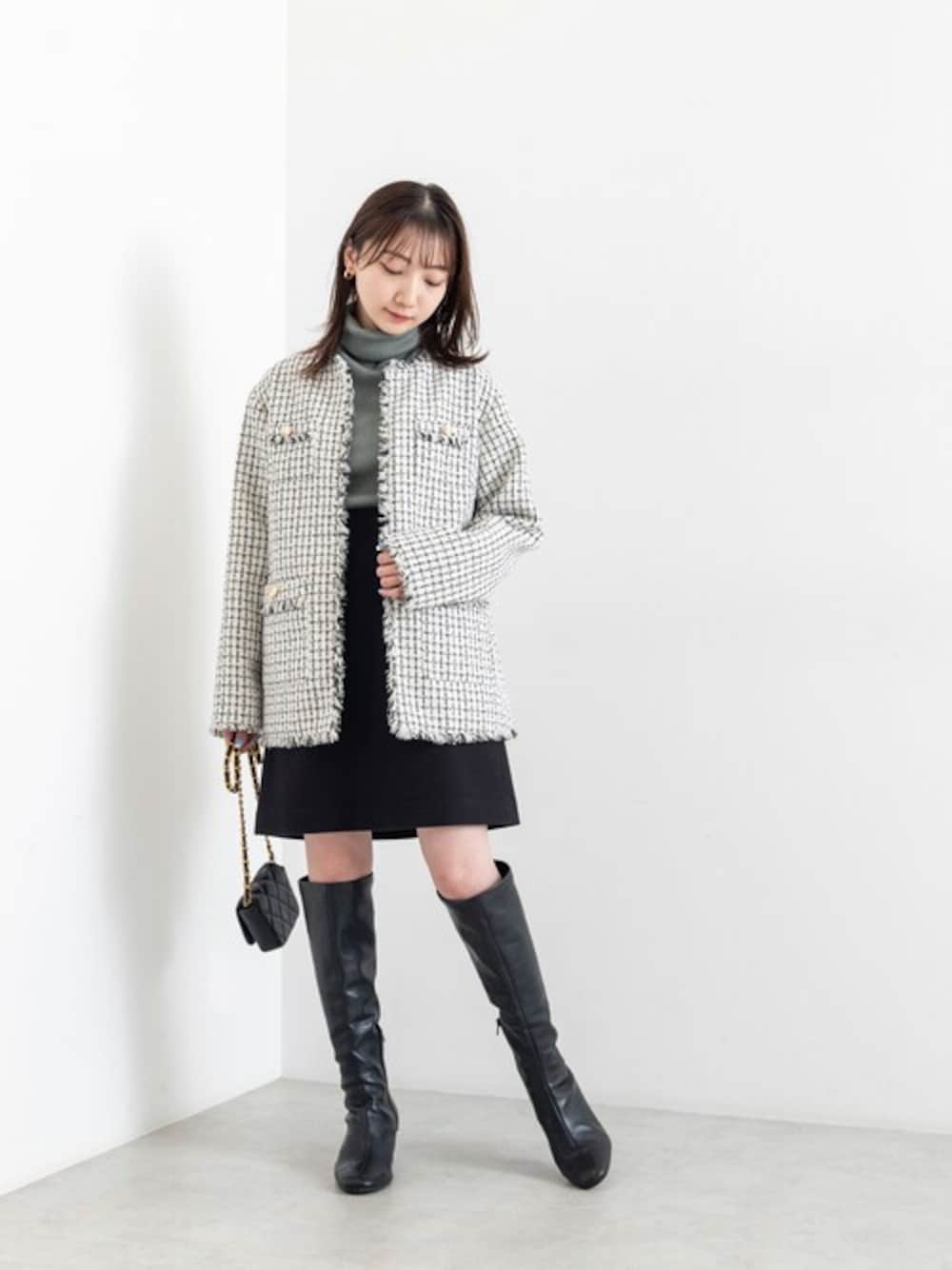 グリーン系のニット/セーター、ブラック系のスカート、ブラック系のショルダーバッグを着用したレディースの秋コーディネートの1枚目の写真