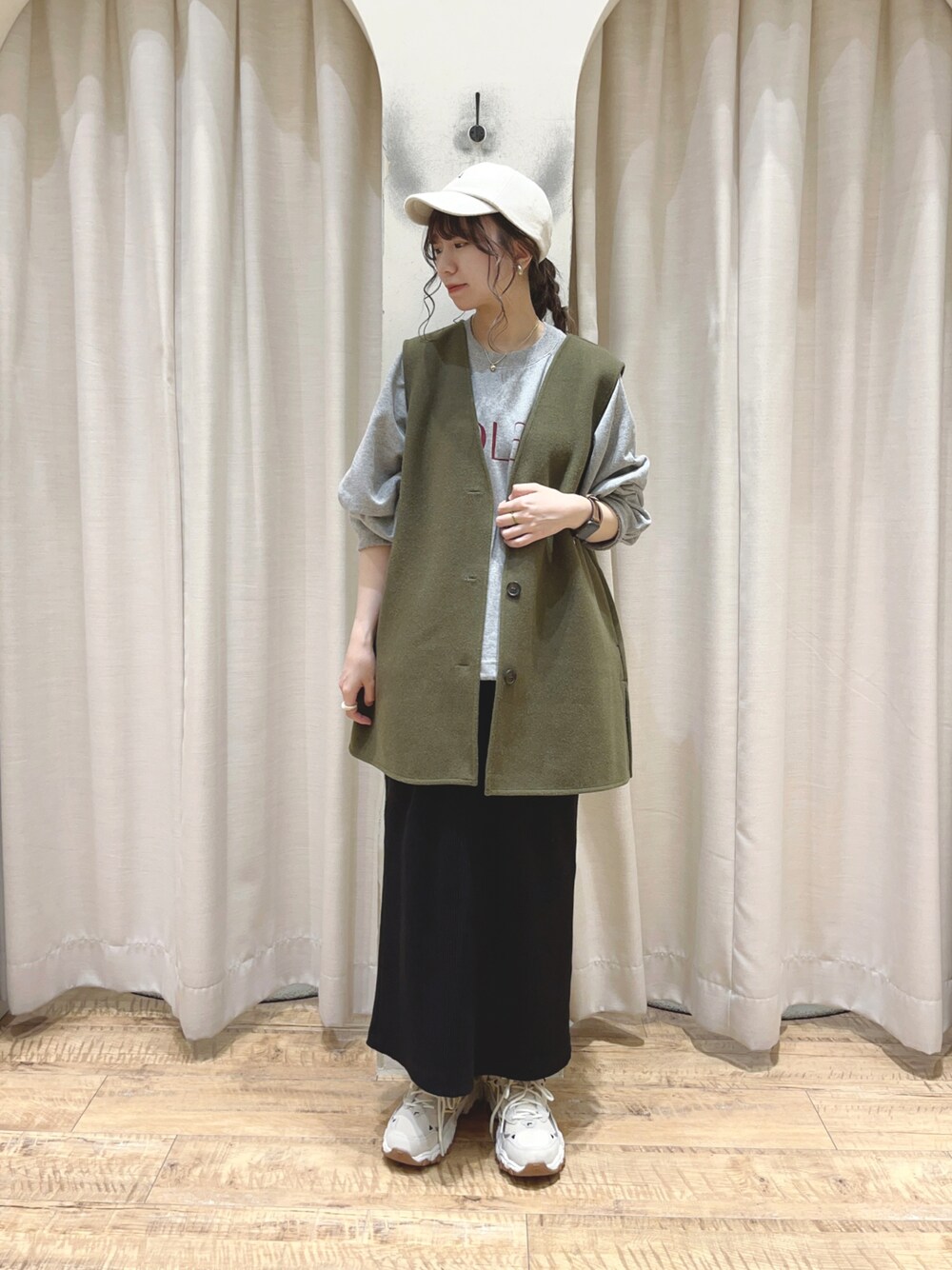 グリーン系のベスト、グレー系のTシャツ/カットソー、ブラック系のスカートを着用したレディースの秋コーディネートの1枚目の写真