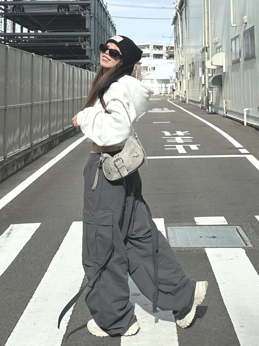 グレー系のカーゴパンツ、グレー系のバッグ、ホワイト系のパーカーを着用したレディースの冬コーディネートの1枚目の写真