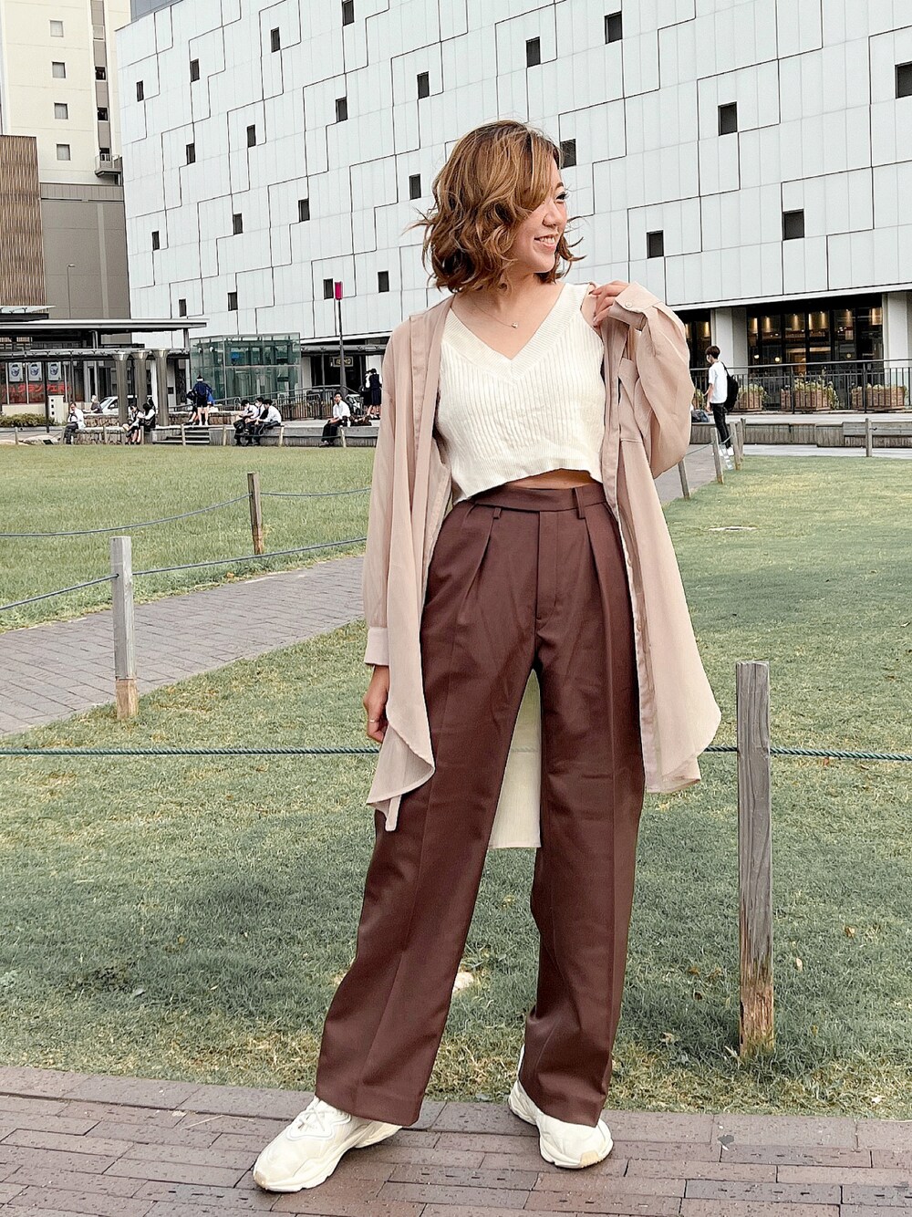 ブラウン系のパンツ、ホワイト系のスニーカーを着用したレディースの秋コーディネートの1枚目の写真